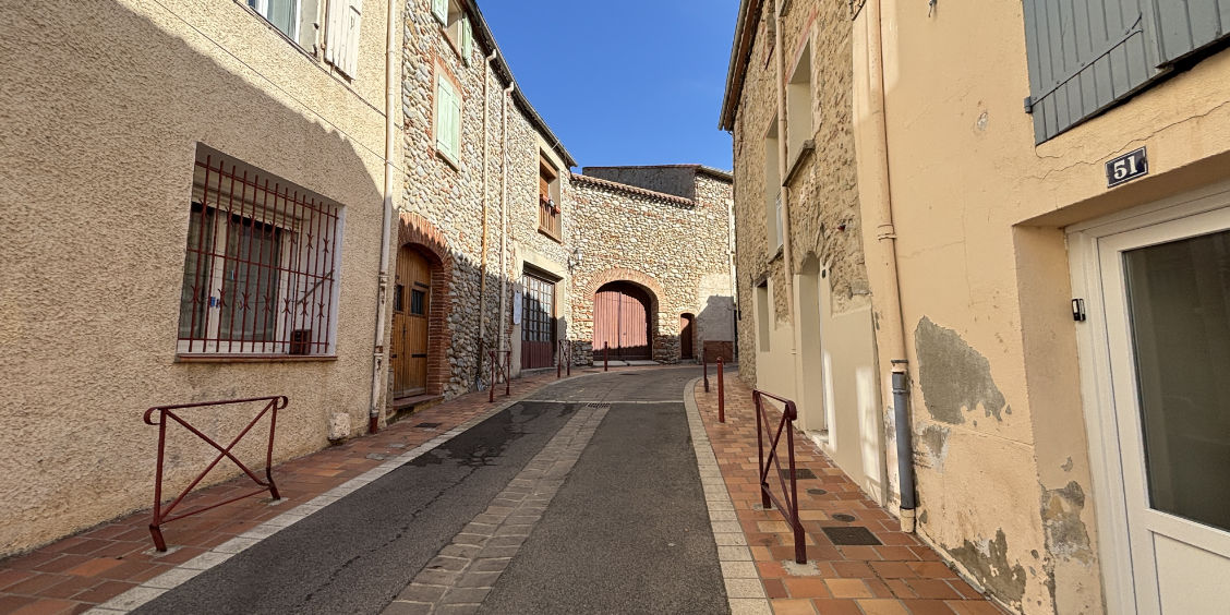 Scorcio di un vicolo caratteristico del centro storico di Le Boulou, con antiche case in pietra nei Pirenei Orientali.