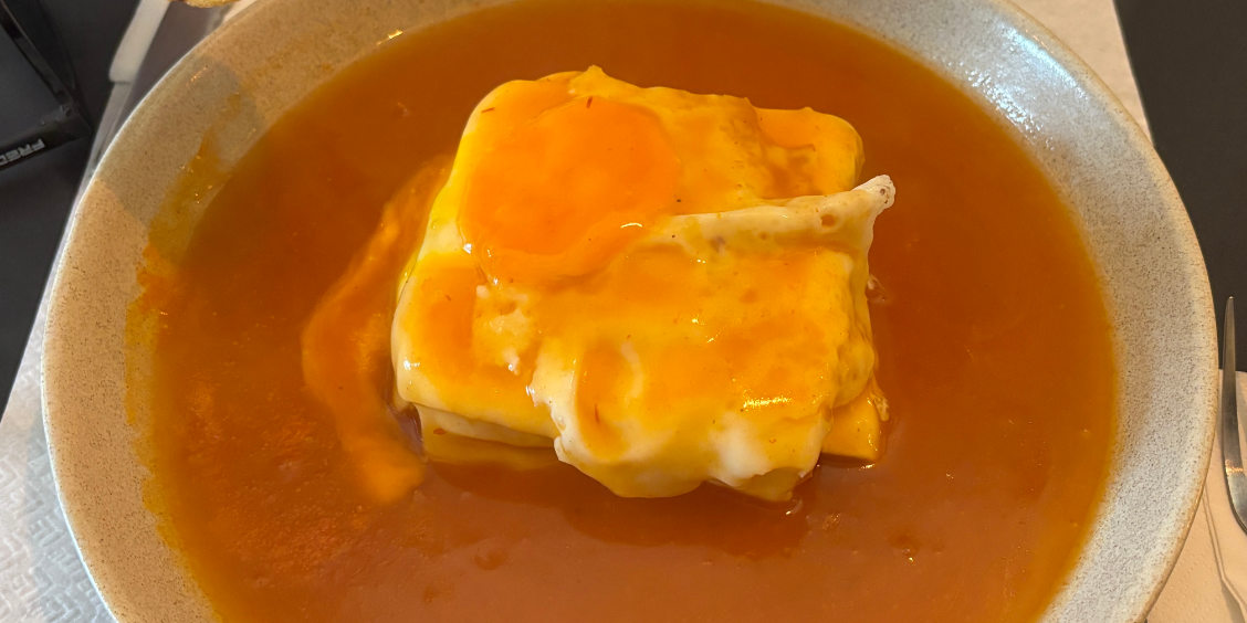 Piatto tradizionale di Francesinha a Porto coperto di formaggio fuso, uovo e salsa piccante.