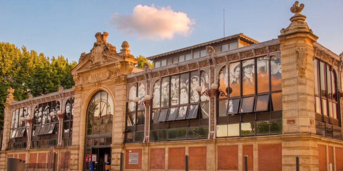 Facciata esterna dello storico mercato coperto Les Halles de Narbonne in Francia, illuminata dalla luce del tramonto.
