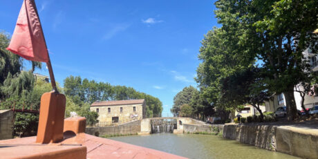 Scorcio panoramico del Canal de la Robine a Narbona, Francia, visto dalla prua di un battello turistico.