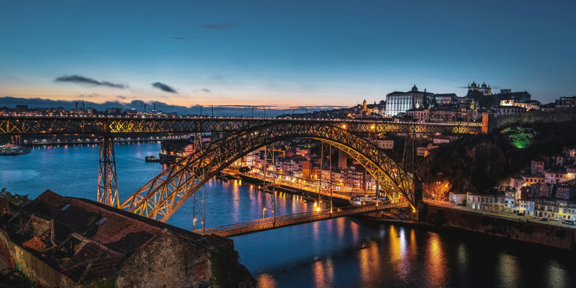 Ponte Dom Luís I e quartiere della Ribeira a Porto illuminati al tramonto sul fiume Douro.