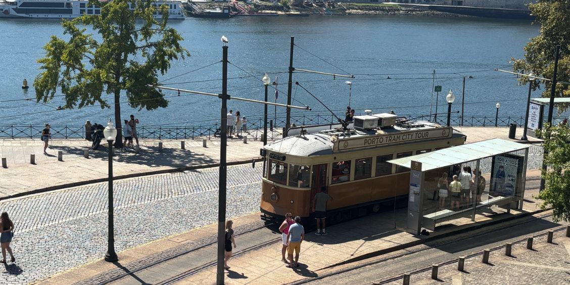 Storico tram di Porto in sosta alla fermata di Praça do Infante lungo la riva del fiume Douro.